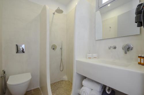 a white bathroom with a toilet and a sink at Prestige on the beach in Naxos Chora