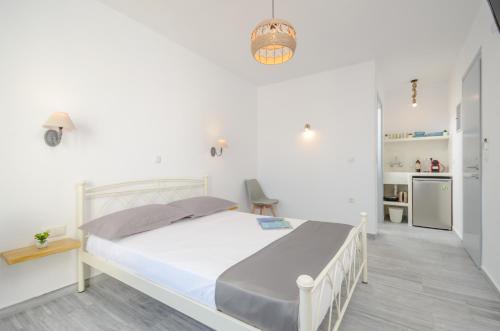 a white bedroom with a bed and a kitchen at Prestige on the beach in Naxos Chora