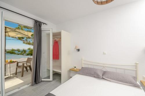 a bedroom with a bed and a balcony with the ocean at Prestige on the beach in Naxos Chora