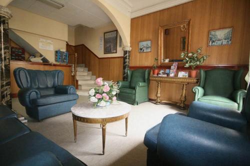 una sala de estar con sillas azules y una mesa con flores en Hostal La Perla Asturiana, en Madrid