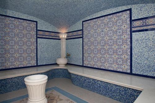 a bathroom with a toilet in a room with blue tiles at Grand Hotel Vidgof in Chelyabinsk