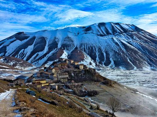 a small town on a mountain in front of a snow covered mountain at Albergo Ristorante Terme in Acquasanta Terme
