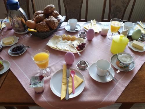 a table with a pink table cloth with breakfast foods and drinks at Gästehaus zum Georgenberg in Goslar