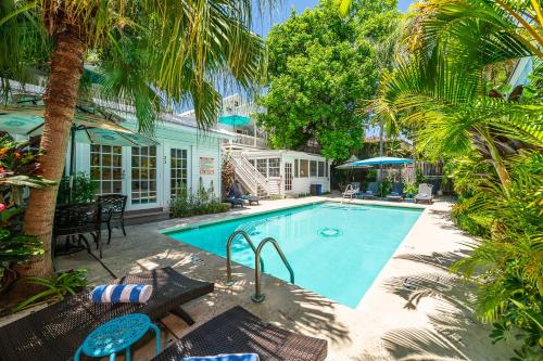a swimming pool with palm trees and a house at Rose Lane Villas in Key West