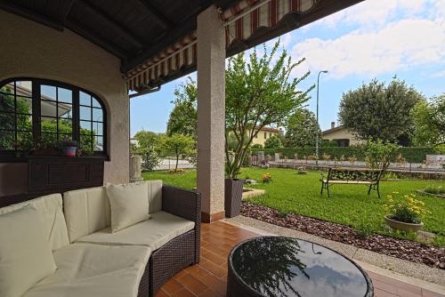 a porch with a couch and a glass table at VECCHIA FAVOLA HOUSE in Quarto dʼAltino