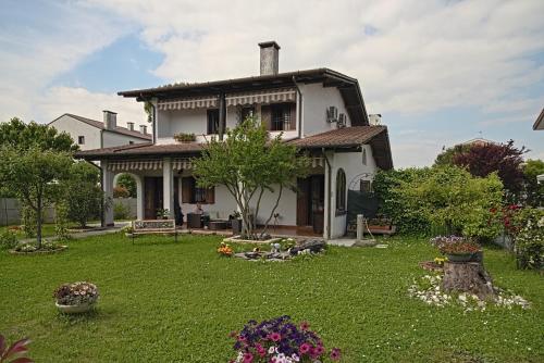 a large white house with a yard with flowers at VECCHIA FAVOLA HOUSE in Quarto dʼAltino