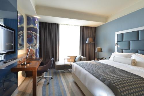 a hotel room with a bed and a desk and a television at Wyndham Grand Istanbul Europe in Istanbul