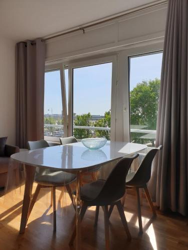 une table de salle à manger avec des chaises et une grande fenêtre dans l'établissement La Vue Sur Mer - Appart avec place de parking, à Boulogne-sur-Mer