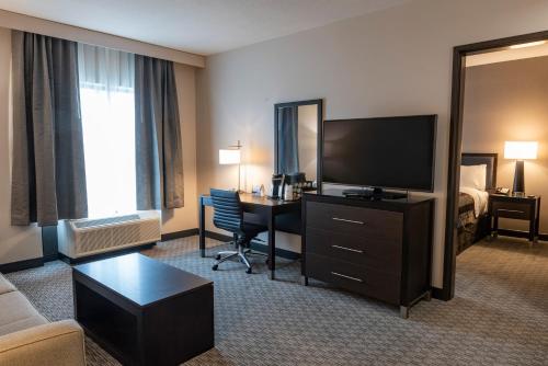a hotel room with a television and a desk with a bed at Wingate by Wyndham Angola in Angola