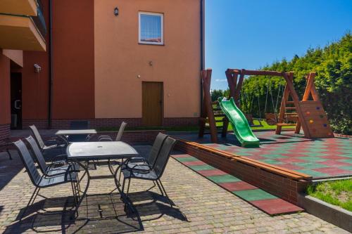 a patio with a table and chairs and a playground at Malinka in Rewal