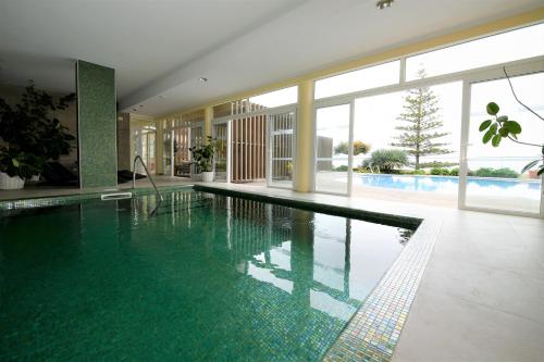 a swimming pool in a building with a large window at Hotel Do Campo in Ribeira Brava