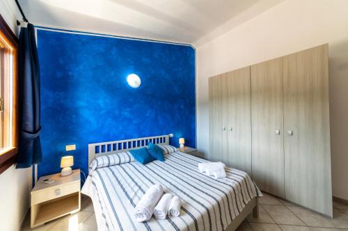 een slaapkamer met een bed en een blauwe muur bij Residence Le Ginestre / Ataras in Porto San Paolo