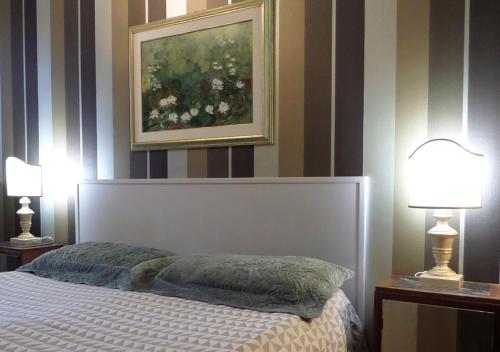a bedroom with a bed with two lamps and a painting at La Finestra sul Fiume in Fossombrone