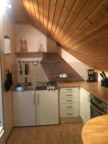 a kitchen with white cabinets and a wooden ceiling at Anexet in Kungsbacka