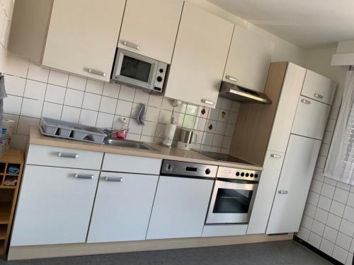 cocina con armarios blancos y microondas en Appartement EuroAirport Basel-Mulhouse-Fribourg en Saint-Louis
