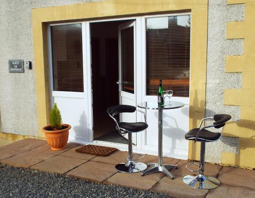 a patio with two chairs and a table in front of a door at Flat 14d Bayhead in Stornoway