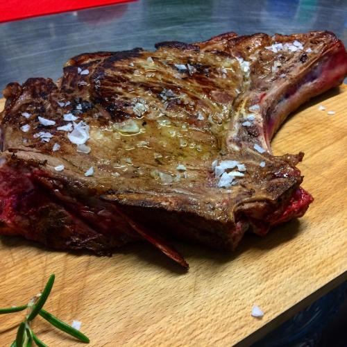 a piece of steak on a wooden cutting board at Agriresort Villa Gelso- Adults Friendly in Vesime