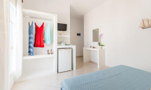 a white room with a bed and a mirror at Anita Rooms & Suites Milos in Adamas