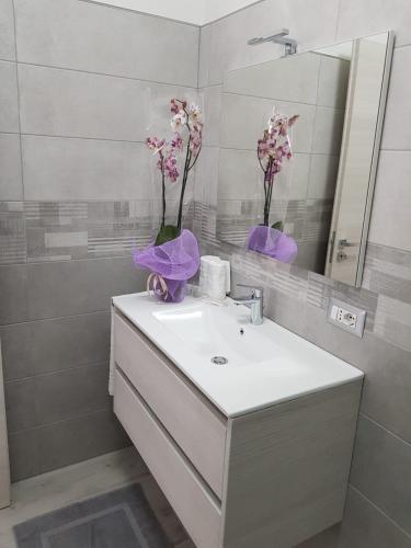 a bathroom with a sink with a mirror and flowers on it at Appartamenti Edia in Lampedusa