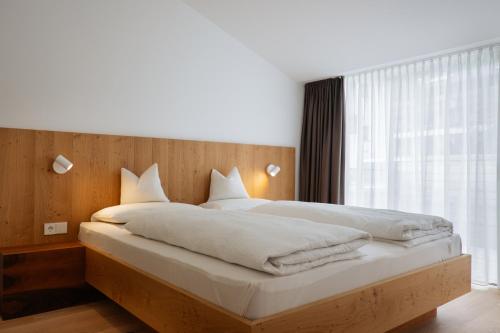 - une chambre avec un lit doté de draps blancs et une fenêtre dans l'établissement Appartement Hell, à Dobbiaco