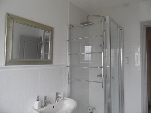 a bathroom with a shower and a sink and a mirror at Tŷ Clûd in Llangefni