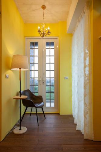 a yellow room with a chair and a lamp at Rambling Snail in Luodong
