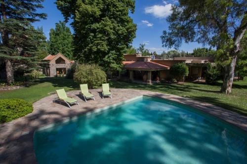 a swimming pool with two chairs and a house at Casa La Galeana - Eco Boutique in Chacras de Coria