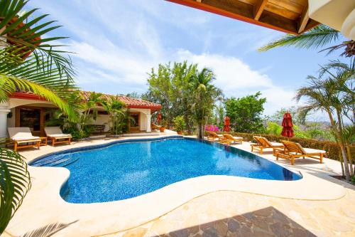 a swimming pool with chairs and a house at Los Altos de Eros - Adults Only in Playa Avellana