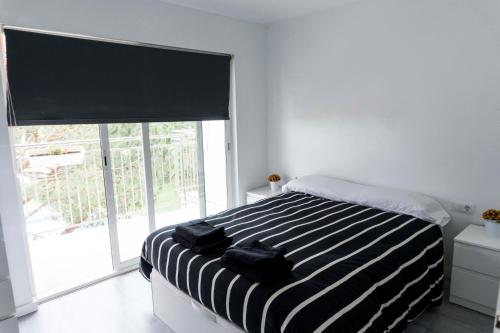 a bedroom with a black and white bed with a window at Precioso apartamento en la playa Barcelona in Cabrera de Mar