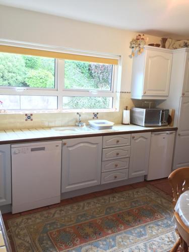 una cocina con armarios blancos y una ventana en Shore Road Enniskillen, en Enniskillen