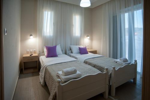 two beds in a bedroom with purple pillows on them at Vanessa's Rooms & Apartments in Kanali