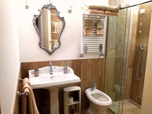 ein Badezimmer mit einem Waschbecken, einem WC und einem Spiegel in der Unterkunft Oltre le mura b&b in Bitonto