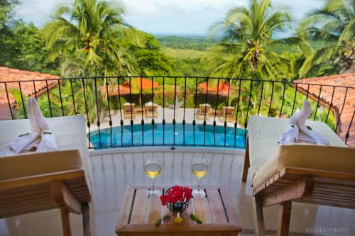 a table with two glasses of wine on a balcony at Los Altos de Eros - Adults Only in Playa Avellana