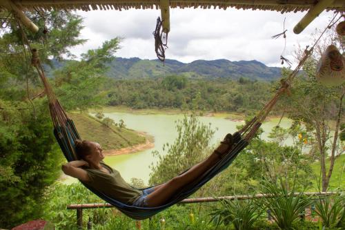 a woman laying in a hammock overlooking a river at Casa Encuentro Ecolodge, Outdoor Gym and Yoga in Guatapé
