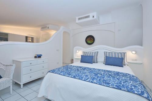 a white bedroom with a large bed with blue pillows at Villa Gelsomina in Ravello