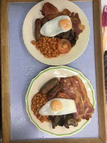 库姆马丁Newberry Beach lodge的桌上有两盘鸡蛋和豆子的食物