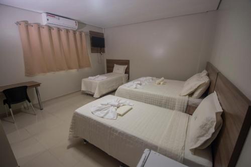 a hotel room with two beds and a desk at Hotel Encosta do Horto in Juazeiro do Norte