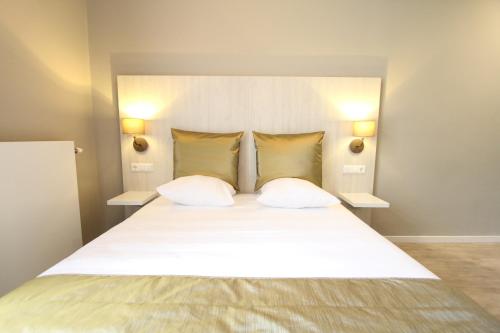 a bedroom with a large white bed with two pillows at Apple Inn Hotel in Amsterdam