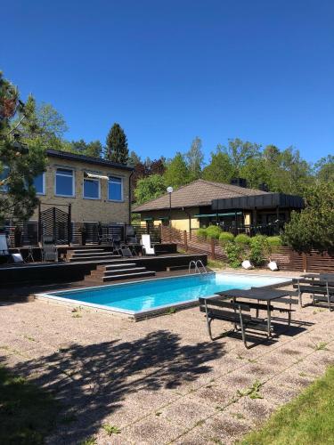 a swimming pool with a picnic table and a house at Yxnerum Hotell in Yxnerum
