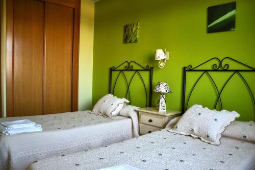 2 camas en una habitación con paredes verdes en Casa Rural Casa Jacinta, en San Cristóbal de Segovia
