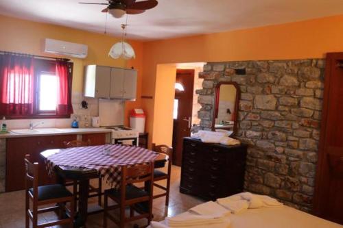 a kitchen with a table and a stone wall at Mani Drosopigi Stonehouse Apartment in Dhrosopiyí