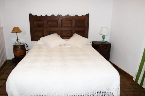a bedroom with a white bed with a wooden headboard at Nido Menas in Torrejón el Rubio