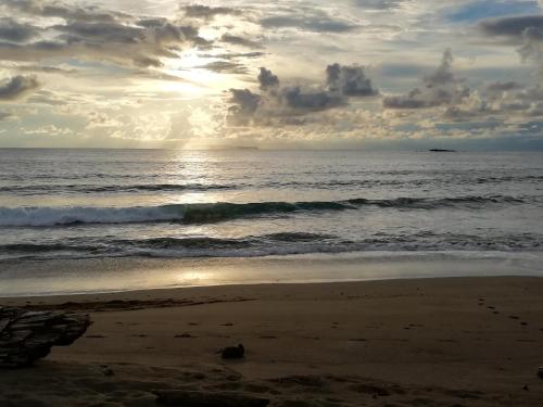 a beach with the ocean and a cloudy sky at Garden of Heliconias Lodge in Drake