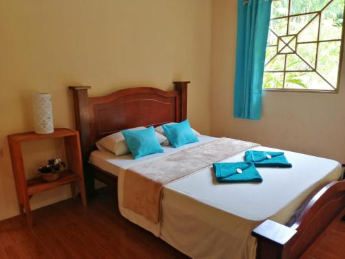 a bedroom with a bed with blue towels on it at Garden of Heliconias Lodge in Drake