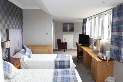 a hotel room with two beds and a desk at South Beach Hotel in Troon