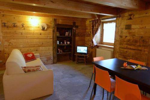 een woonkamer met een tafel en stoelen en een televisie bij Vieilles Maisons D'Introd in Introd