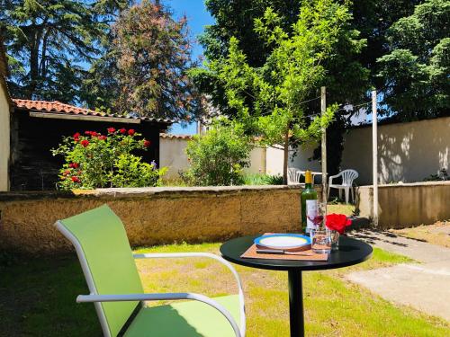 - une table avec une chaise verte et une table avec une bouteille de vin dans l'établissement Studio Cosy avec Jardin, à Roanne
