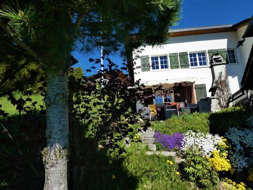 a house with a tree and flowers in the yard at Casa Fluretta in Flumserberg