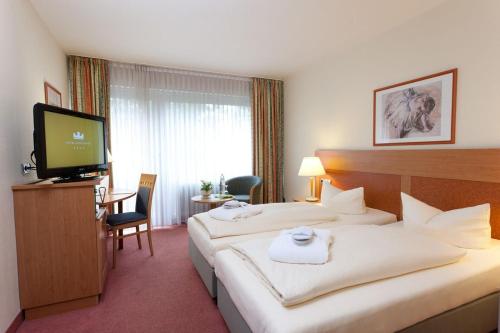 a hotel room with two beds and a flat screen tv at Hotel Königshof in Garmisch-Partenkirchen