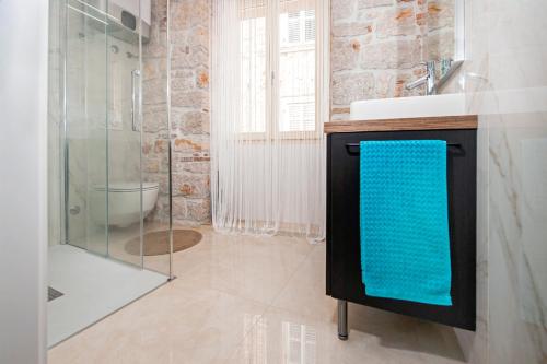 La salle de bains est pourvue d'un lavabo et d'une douche avec une serviette bleue. dans l'établissement Apartments Sea View - Sunrise and Maremonte, à Rovinj